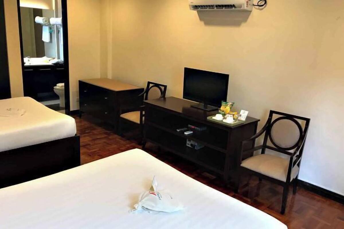 Una habitación de hotel con una cama, un escritorio con una computadora, una silla y un televisor.