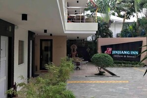 A hotel entrance with a sign, a covered outdoor seating area, and a small garden. - Jinjiang Inn - Boracay Station 1 (Boracay Island)
