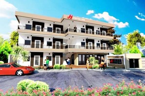A multi-story hotel with a modern design, featuring balconies on each floor, a parking area, and a landscaped garden with flowers. - Jinjiang Inn - Boracay Station 1 (Boracay Island)