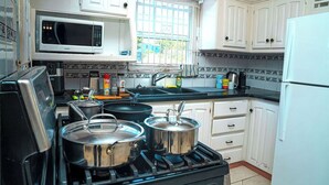 A kitchen with white cabinets, a microwave, a stove, and a refrigerator. - Sol Springs Estate (Osbourn)