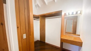 A hallway with a wooden door, a vanity with a mirror and lights, and a staircase leading to another room. - Sol Springs Estate (Osbourn)