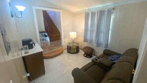 A compact living space with a kitchenette, a sofa, a small table, and a lamp. - Sol Springs Estate (Osbourn)