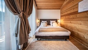Ein Schlafzimmer mit Holzbalkendecke, einem Bett mit Kopfteil, Nachttischlampen und einer gerahmten Karte an der Wand.