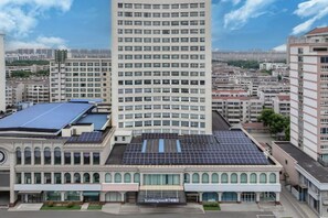 A hotel with a central courtyard, a tall building with a curved facade, and a flat-roofed building with solar panels.