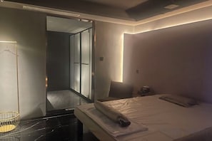Moderni hotellihuone, jossa on sänky, yöpöytä ja peili.