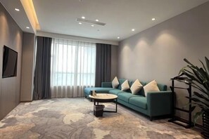 A modern living room with a sofa, a coffee table, and a large window with curtains.