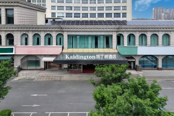 A hotel with a modern facade, a covered entrance, and a parking lot in front.