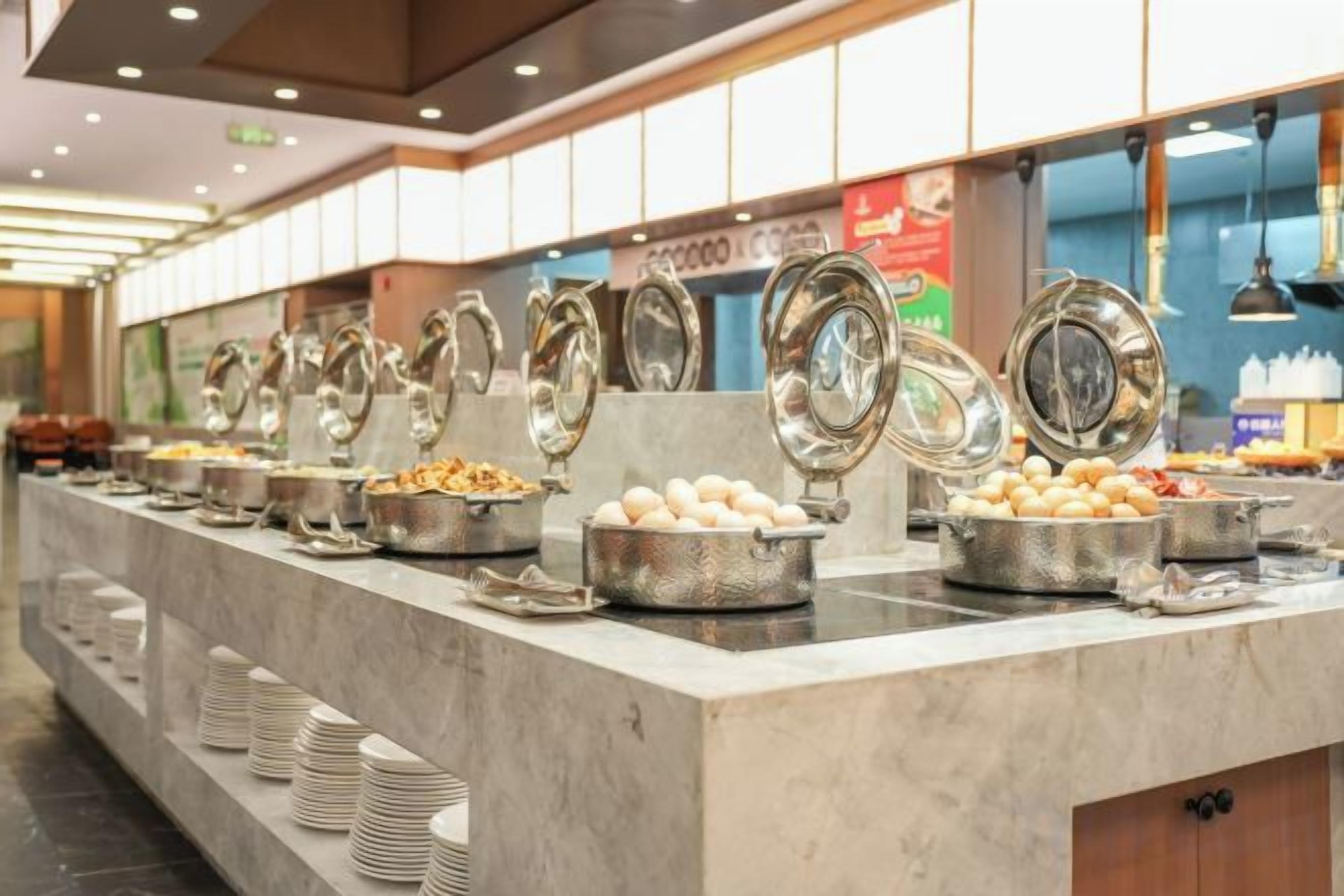 A buffet with multiple food stations, each with a metal serving tray and lid.