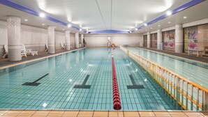 Piscina interna com paredes e piso azulejados, e um separador de pistas central.
