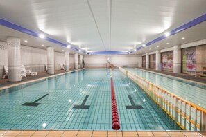 Una piscina interior con paredes y suelo de baldosas, y un separador central de carril.