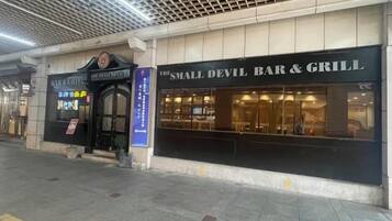 Um edifício com uma fachada identificada como 'The Small Devil Bar & Grill'.