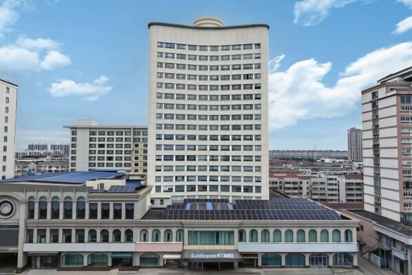 A multi-story building with a curved facade, large windows, and a flat roof with solar panels.