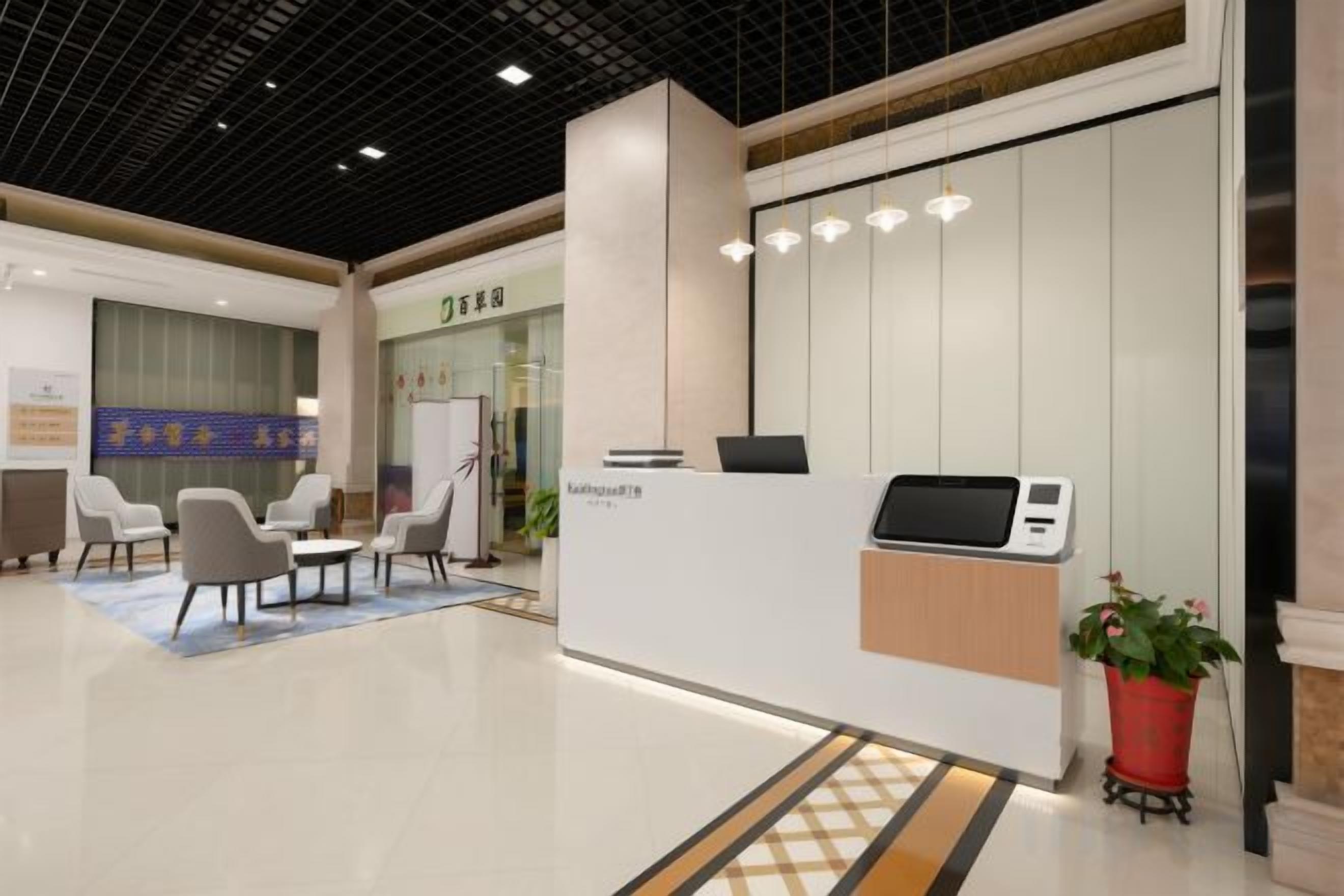 A reception area with a reception desk, chairs, a potted plant, and a wall-mounted screen.