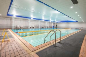 An indoor swimming pool with clear lanes, a tiled floor, and a blue ceiling. - Guomao Boutique Hotel (Zhangjiagang)