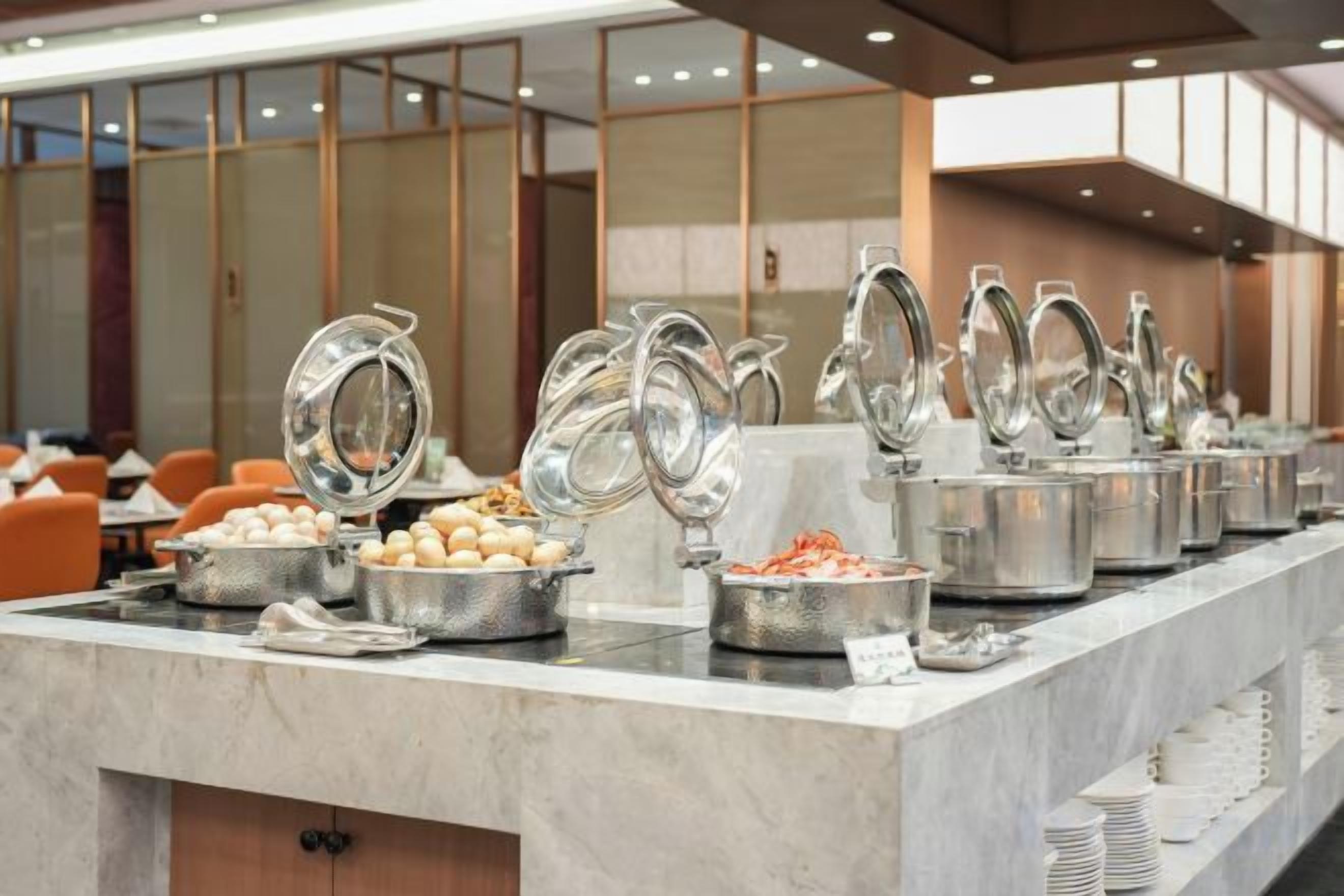 Montaje de bufé con varias estaciones de servicio, incluyendo tazones de comida y bebidas calientes.