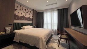 A hotel room with a bed, bedside table, TV, and a desk. - Guomao Boutique Hotel (Zhangjiagang)