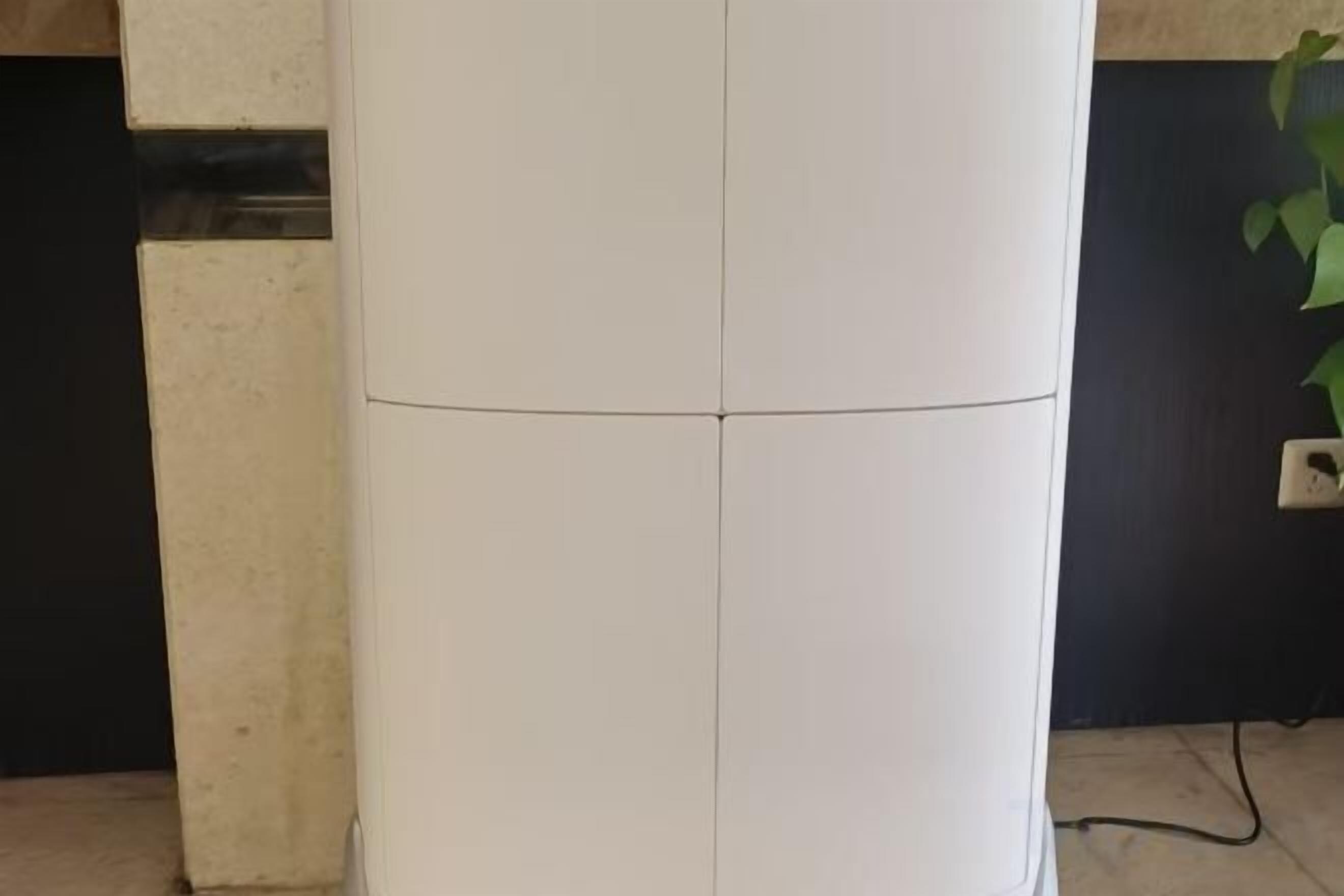 A white cylindrical object, possibly a pillar or column, with a visible cable or wire at its base.