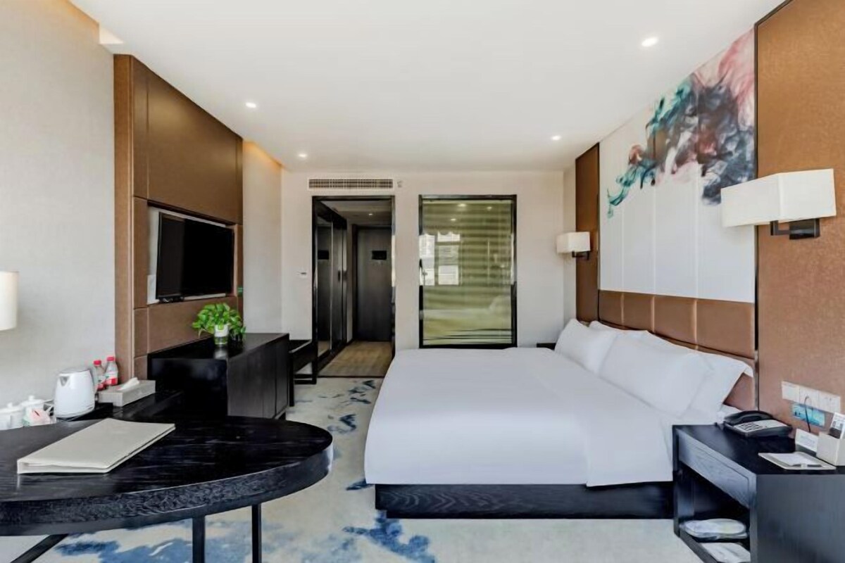 A hotel room with a bed, a desk, a TV, and a bathroom.