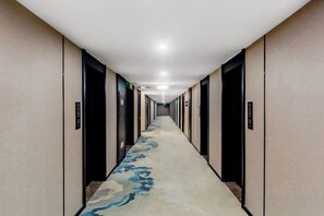 A hotel corridor with a carpeted floor, doors on both sides, and a ceiling with recessed lighting. - HSH Cozy Hotel (Wuhu)