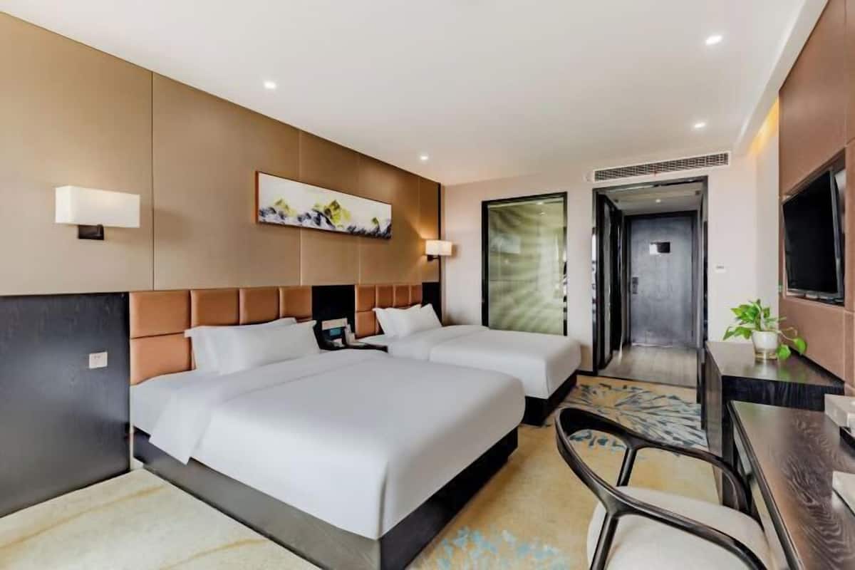Quarto de hotel com uma cama grande, duas mesas de cabeceira, uma escrivaninha e uma cadeira.