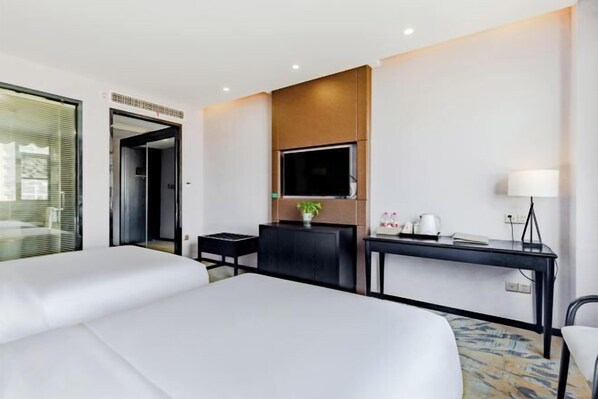 A hotel room with two beds, a desk, a TV, and a lamp. - Hsh Cozy Hotel (Wuhu)