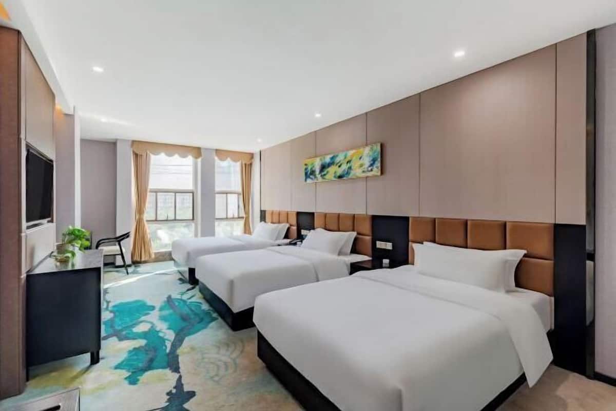 Quarto de hotel com duas camas, uma escrivaninha, uma televisão e uma janela com cortinas.