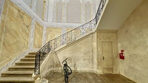 Un magnifique escalier, orné de rampes noires travaillées, et un vélo garé en bas.