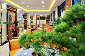 A hotel lobby with seating areas, a reception desk, and a television screen. - Building a Grand Hotel (Jingtai)