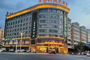 A multi-story hotel with a curved facade, large windows, and illuminated signage.