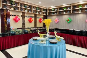 Montaje de bufé con mantel azul, un jarrón con flores amarillas y una variedad de platos.