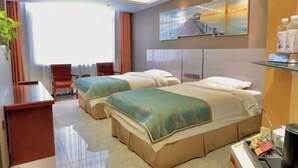 Habitación de hotel con dos camas, un escritorio, una silla, un ventanal grande y un cuadro en la pared.