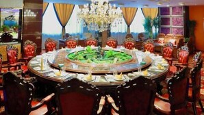 Una mesa redonda para comer con sillas tapizadas en rojo, una araña y un centro de mesa decorativo.
