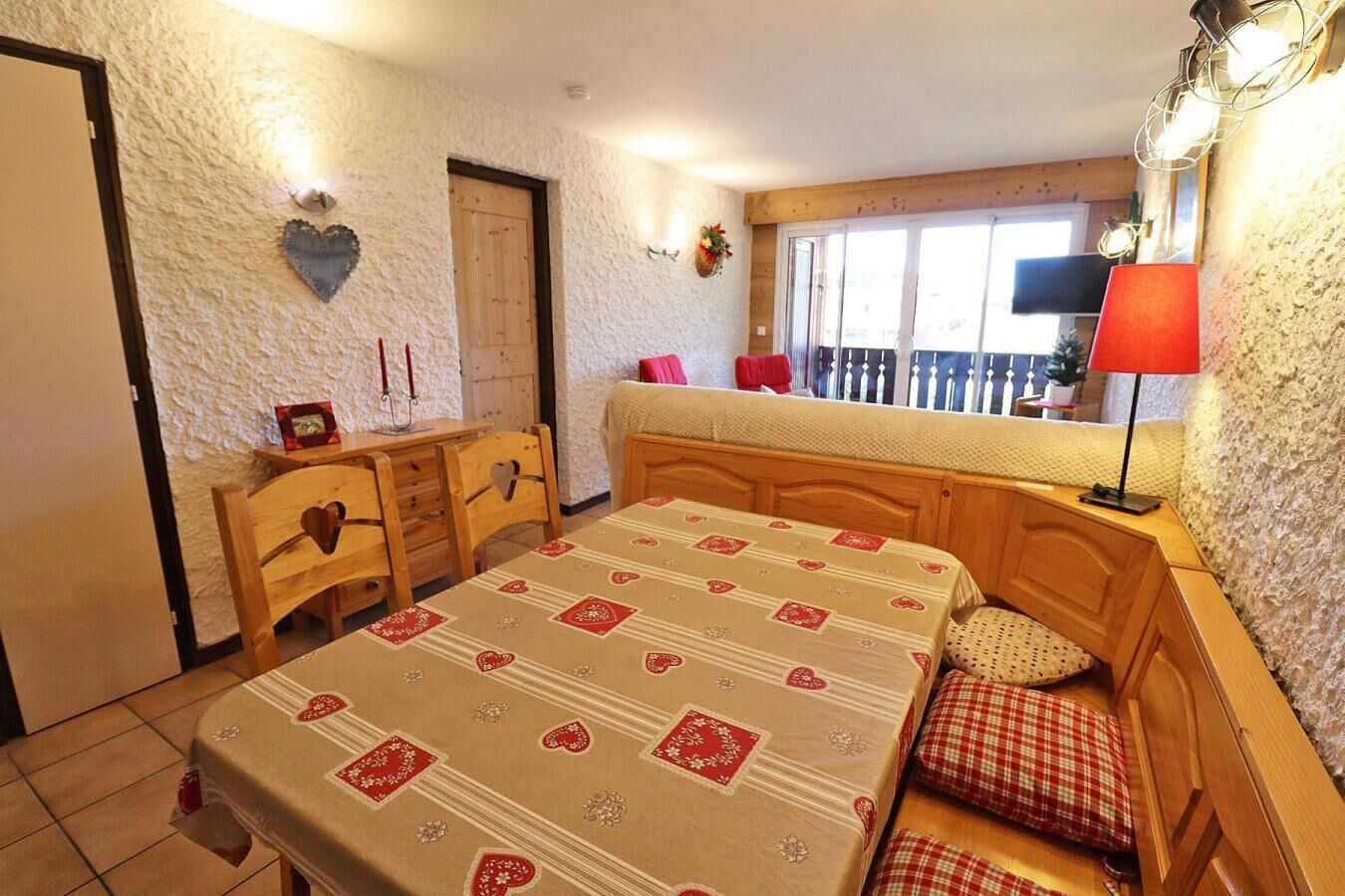 A bedroom with a bed, a desk, and a window.