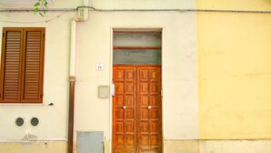 Μια διπλή ξύλινη πόρτα με ένα μικρό παράθυρο ακριβώς από πάνω, τοποθετημένη σε ένα κτίριο με πλακάκια στο δάπεδο και έναν κ ίτρινο τοίχο.