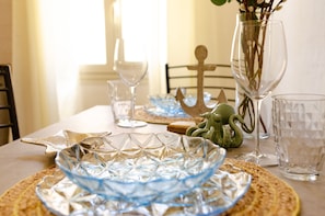 A dining table set with glassware, plates, and a decorative anchor centerpiece.