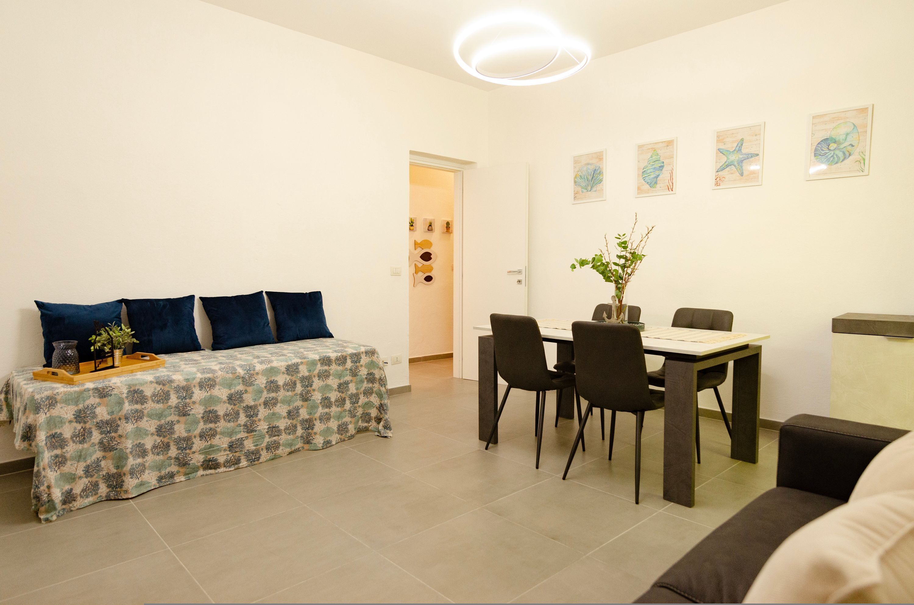 Ein modernes, helles Zimmer mit einem Bett, einem Esstisch mit Stühlen und einem kleinen Tisch mit einer Pflanze.