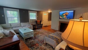 A living room with a sofa, a coffee table, a TV, and a fireplace. - 3 Bedroom house, close to the beach and beech forest. (Eastham)