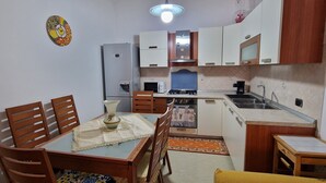 Une cuisine compacte comprenant une table à manger, des chaises, un réfrigérateur, un four à micro-ondes, une cuisinière et un évier.