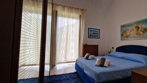 Une chambre à coucher avec un lit, un tableau et une fenêtre avec des rideaux.