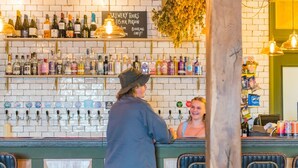 Een bar met verschillende drankflessen en een bord dat brouwerijrondleidingen aangeeft.