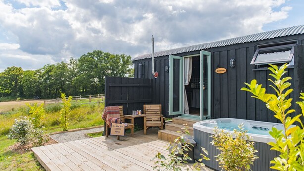 Une cabane en bois dotée d’un bain à remous, d’une terrasse couverte et d’une enseigne indiquant « Cascade ».
