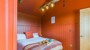 Um quarto com uma cama, uma porta de madeira e uma parede com um aviso.