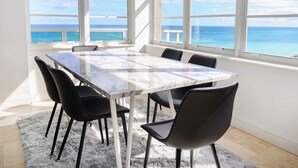 A room with a marble table and black chairs, large windows with a view of the ocean. - 2bd Oceanfront Master Ste OceanView w/balcony, Pool, nearby dining, beach access (Miami Beach)