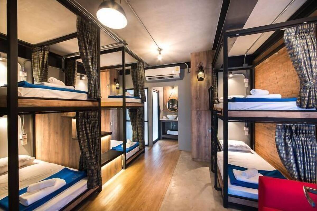 Ein kleines Hotelzimmer mit Etagenbetten, Holzwänden und einem zentralen Gang.