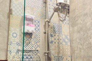 Una ducha con pared de azulejos estampados y cabezal de ducha de mano.