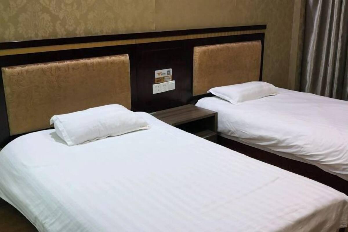 Una habitación de hotel con dos camas individuales, un cabecero de madera y una mesita entre ellas.
