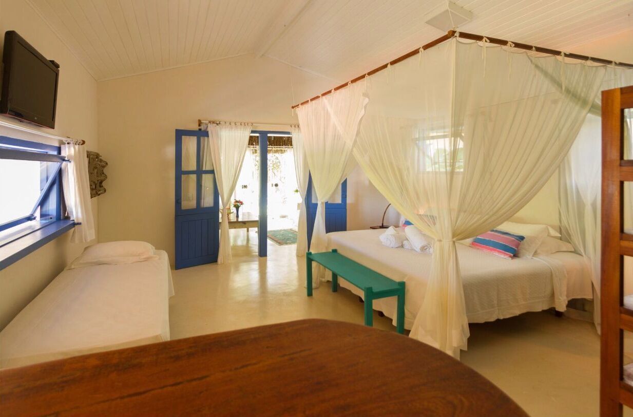 Una camera da letto con un letto a baldacchino, una panca e una TV appesa al muro.