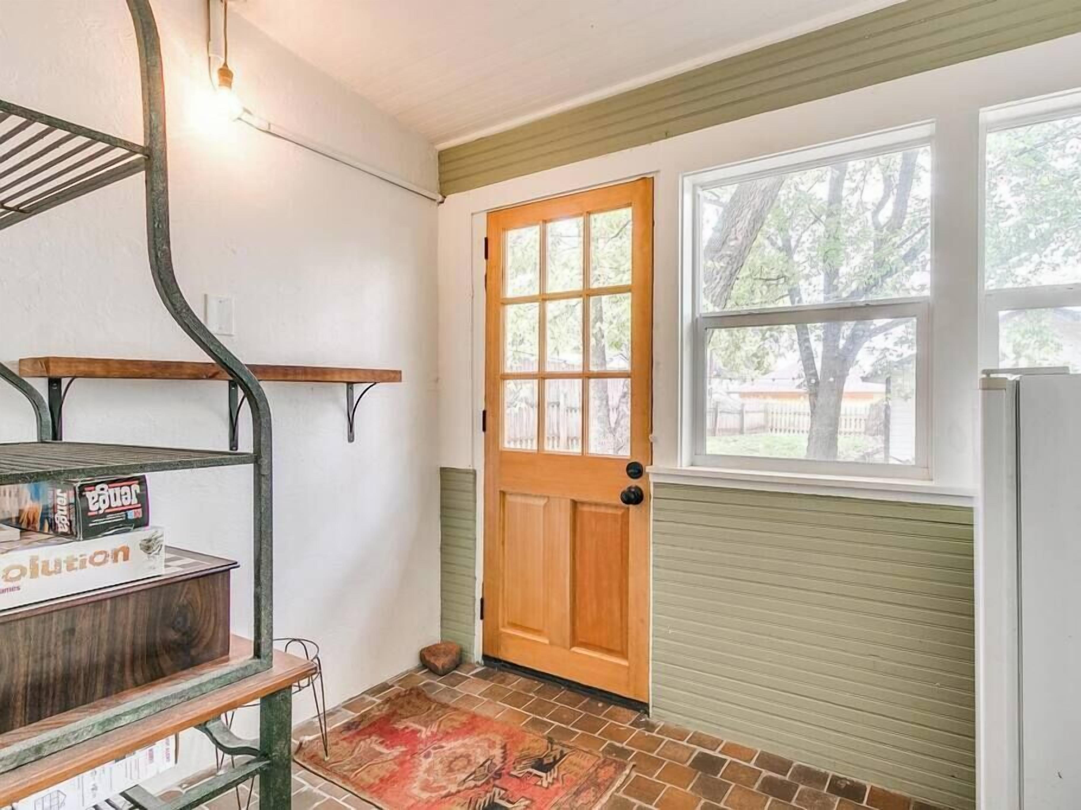 A room with a wooden door, a window, a radiator, and a shelf with a box.