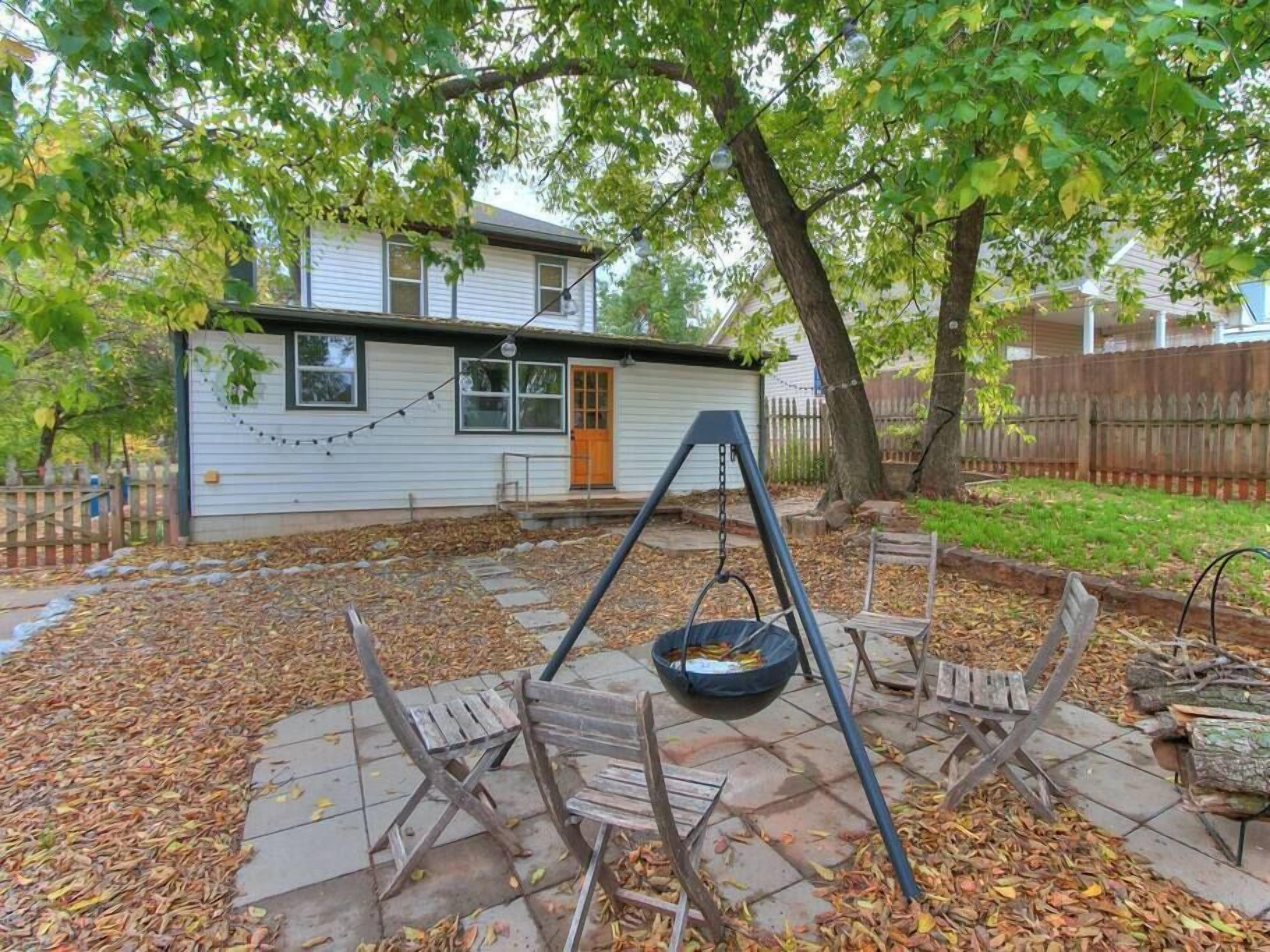 Een achtertuin met een schommel, een tuinhuisje en een woonhuis.