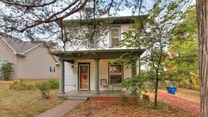 A two-story house with a covered porch and a front door. - Nestled Victorian Historic Area (Guthrie)